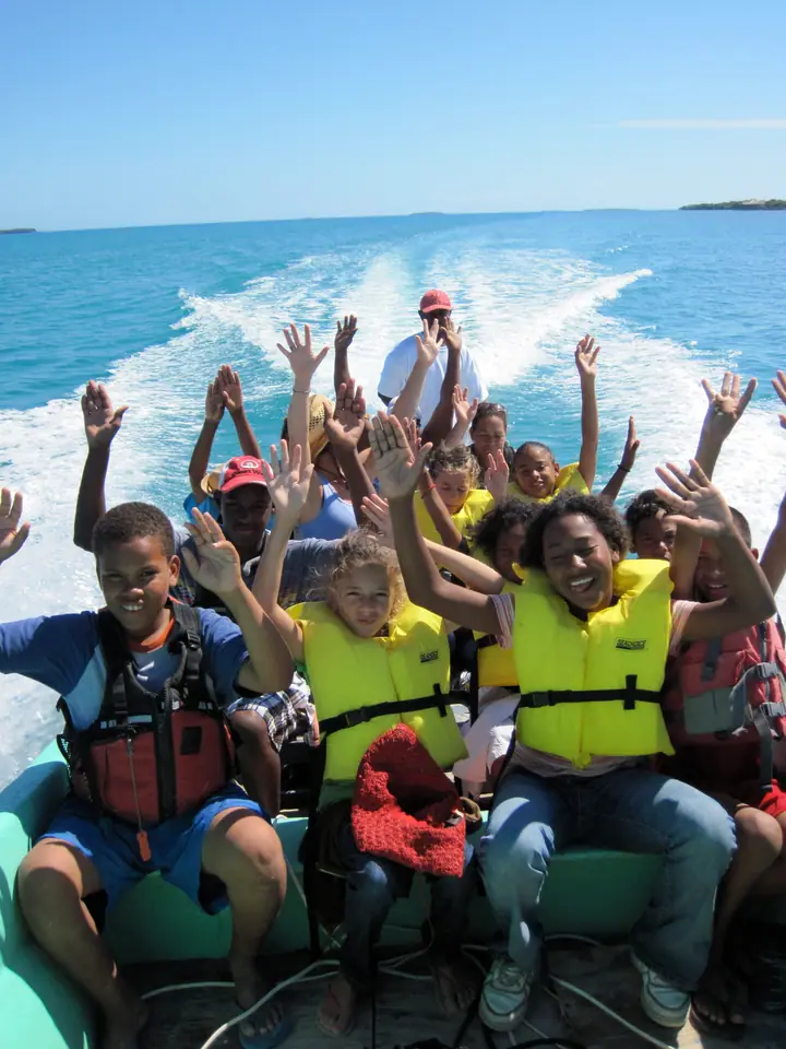 Students in life jackets cheering on a boat ride