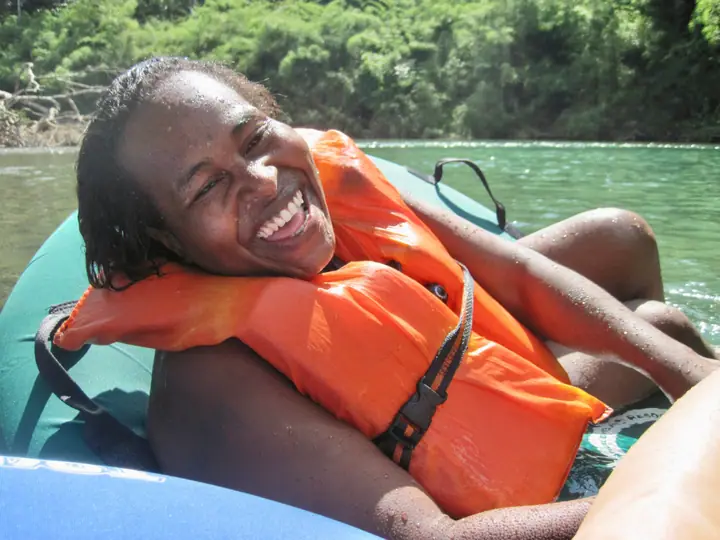A student laughing in a life jacket on an inner tube