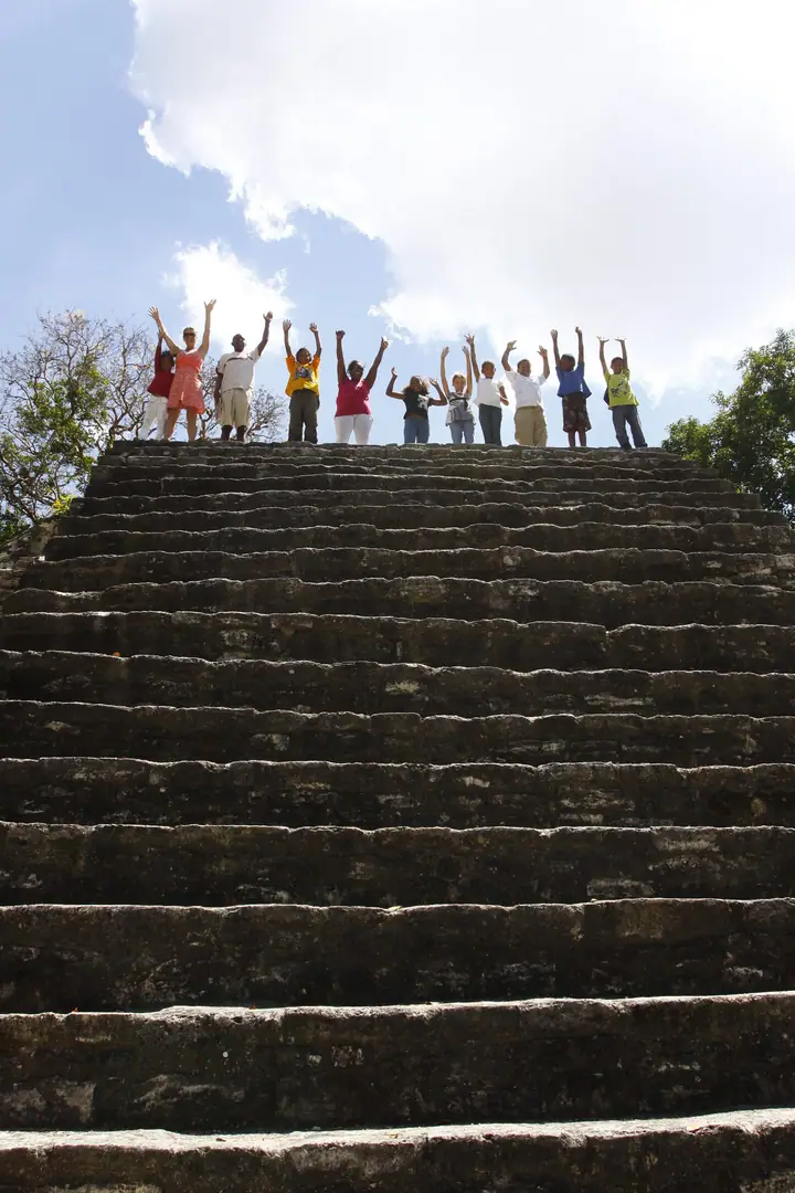 Students with their arms raised on the steps of a Mayan temple
