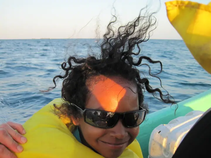 A student in sunglasses and a life jacket out on the water