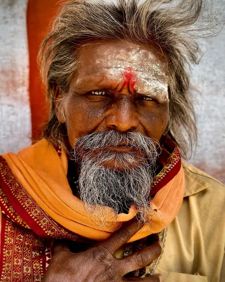 A man with a red tilak and a long grey beard