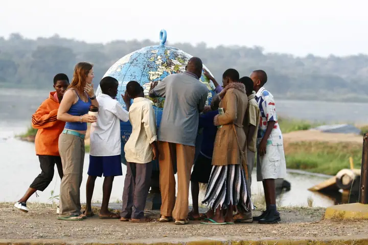 Students and a volunteer gather around a giant globe beside the Nile