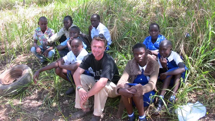 Todd sitting in the grass with a group of students