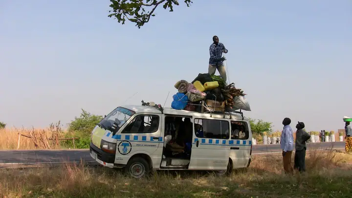 The van on the road with a student riding on the roof