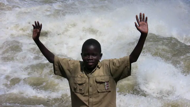 A student throws up his arms in front of the rushing falls